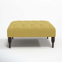 an ottoman with wooden legs and a yellow upholstered cushion on top of it