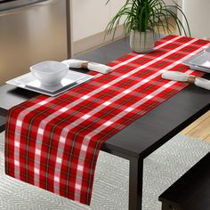 a red and white plaid table runner on a dining room table with place settings for two