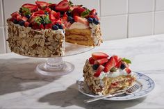 a cake with strawberries and blueberries is on a plate next to the cake