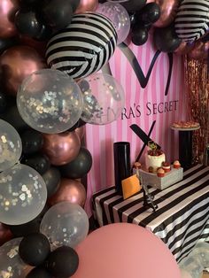 a table with balloons, cake and other items on it in front of a pink striped wall