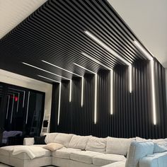 a large white couch sitting in front of a black and white wall with lights on it