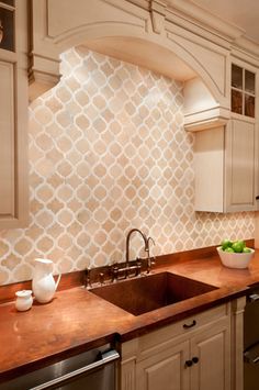 a kitchen with white cabinets and wooden counter tops next to a sink, dishwasher and oven