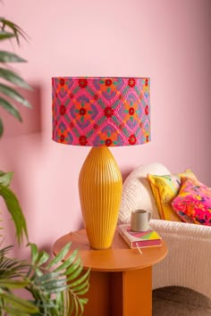 a yellow table lamp sitting on top of a wooden table next to a white chair