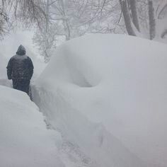 a man is walking through deep snow in the woods