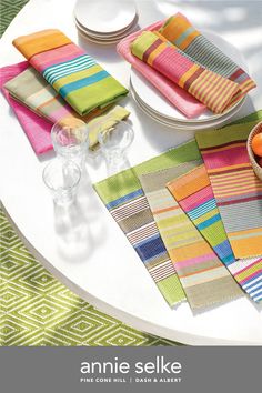 the table is set with colorful napkins and placemats on top of it