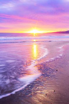 the sun is setting over the water at the beach with waves coming in to shore