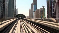 a train traveling through a large city next to tall buildings on either side of the tracks