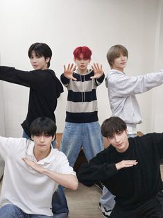 four young men sitting on the floor with their hands in the air