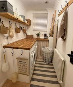 a small laundry room with wooden shelves above the washer, dryer and radiator