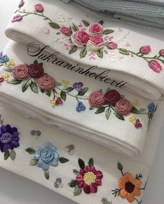 three rolls of embroidered fabric with flowers and words on the side, sitting next to each other