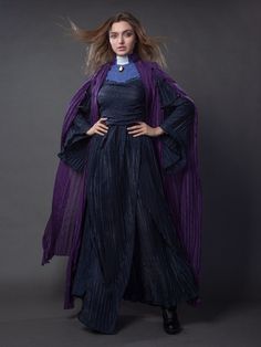 a woman with long hair wearing a black dress and purple cape