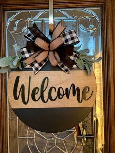 a welcome sign hanging from the front door with a bow on it's head