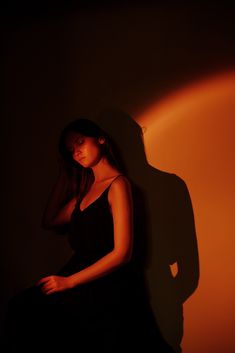 a woman in a black dress is posing for the camera with her shadow on the wall