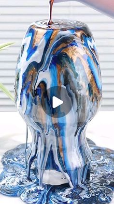 an apple is sitting on top of a blue and white marbled object with a red liquid pouring out of it