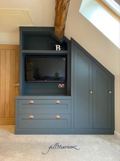 an entertainment center with built - in cabinets and a tv on the wall, under a slanted roof