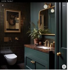 a bathroom with green and gold fixtures, black tiles and a painting on the wall