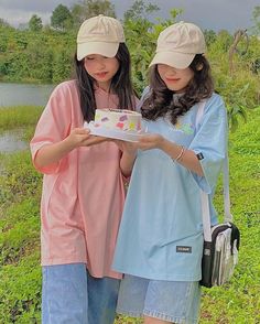 two young women standing next to each other holding a cake