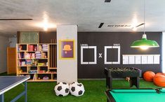 an indoor playroom with foosball, pool table and soccer balls on the grass