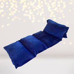 a blue pillow is laying on top of a white surface and some lights are in the background