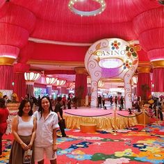 two women standing in front of a casino floor with red and yellow decorations on it