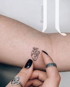 a woman's arm with two tattoos on it, one is holding the other