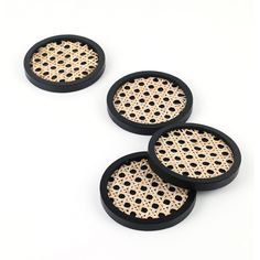 three black and white coasters with holes in them on a white surface, set against a plain background