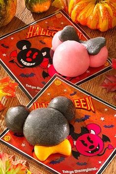 three mickey mouse magnets sitting on top of a wooden table next to pumpkins