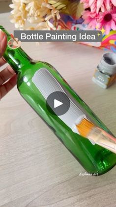 someone is holding a green bottle with paint on it