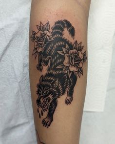 a black and white tattoo of a wolf with flowers on it's back leg