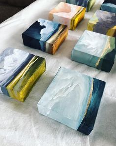 several different colored boxes sitting on top of a white cloth covered table with blue, yellow and green paint