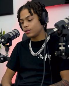 a young man wearing headphones sitting in front of microphones