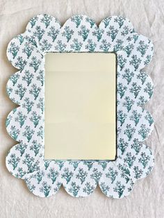 a white and blue flower shaped mirror on a sheet of paper with an empty square in the middle