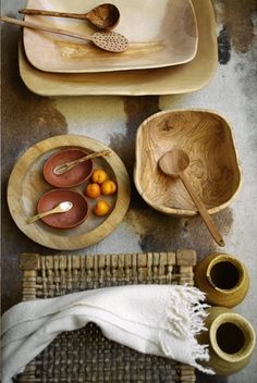 bowls, plates and spoons are arranged on a table