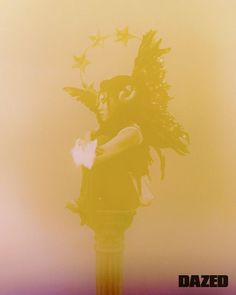 a woman with feathers on her head standing next to a street light