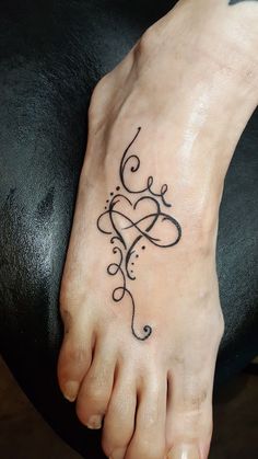 a person with a tattoo on their foot that has an intricate design in the shape of a heart