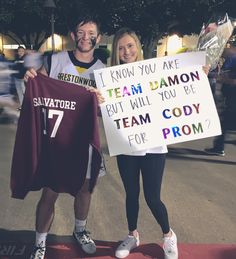 a man and woman holding up signs in the street