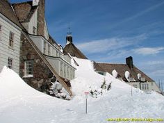 an old house with snow on the ground and stairs up to it's roof