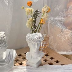 a vase with flowers in it sitting on a table next to a lace covered curtain