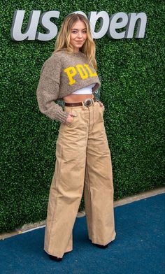 a woman standing in front of a green wall with the words us open on it