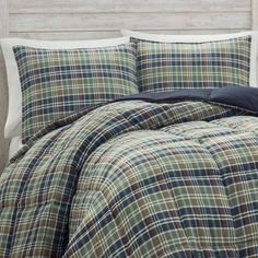 a bed with plaid comforter and pillows on it