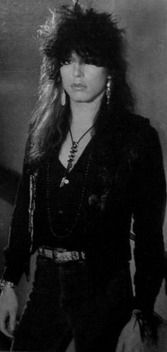 a black and white photo of a woman with long hair in an old fashion outfit