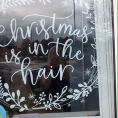 a woman taking a selfie in front of a window with the words christmas is in the rain written on it