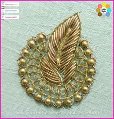 an embroidered brooch with gold beads and a feather on it's back side