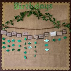 a birthday banner with green leaves and pictures hanging from it's sides on a burlap background