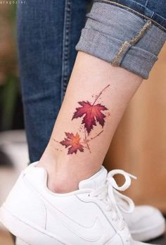 a woman's foot with a red maple leaf tattoo on her left side ankle