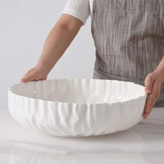 a person holding a white bowl on top of a table