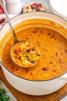 a spoon full of soup sitting on top of a wooden cutting board