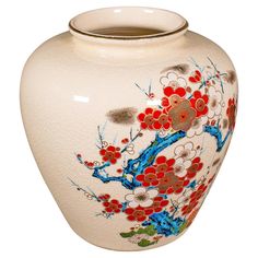 a white vase with red and blue flowers painted on the outside, sitting in front of a white background