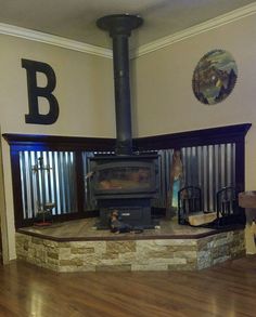 a wood burning stove in a living room with wooden floors and wall art on the walls