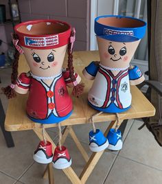 two paper mache dolls sitting on top of a wooden table next to each other